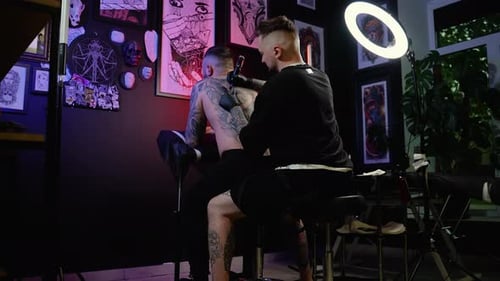 Tattoo Artist tattooing a man in tattoo parlor