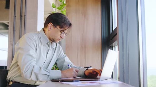 In a Sleek Modern Office Setting a Dedicated Businessman Professional is Intensely Focused on His