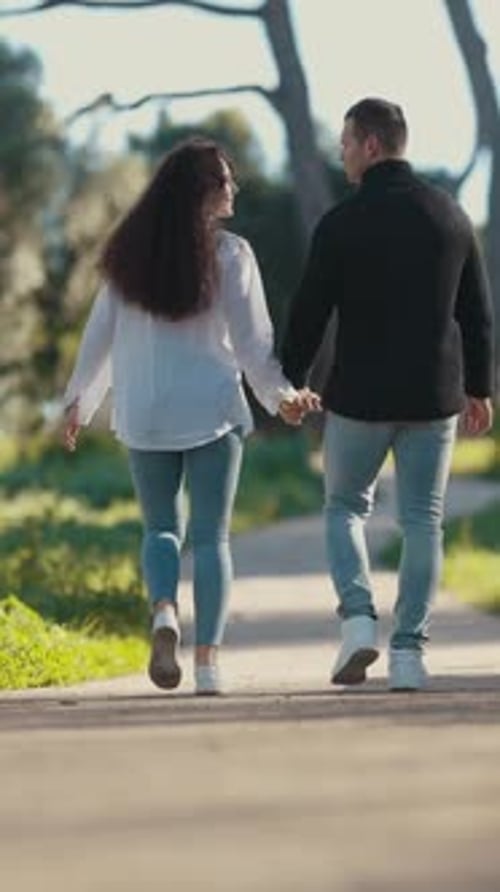 Young Couple Walking Hand in Hand in a Park