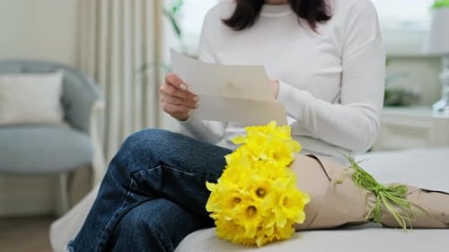 Woman Reads Letter with Yellow Flower Bouquet