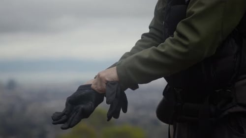 Traveler putting on gloves outdoors on cloudy day
