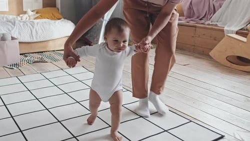 Baby Taking First Steps at Home with Assistance