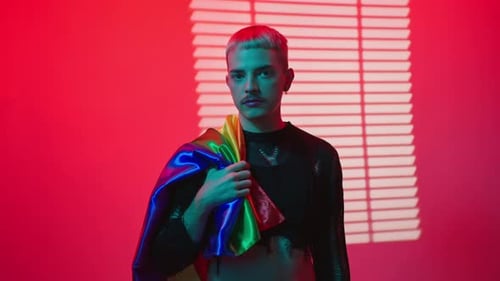 Young Adult Holding Pride Flag in Red Blue Lighting