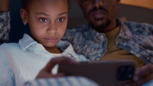 Girl Watching Phone With Man in Bed at Night