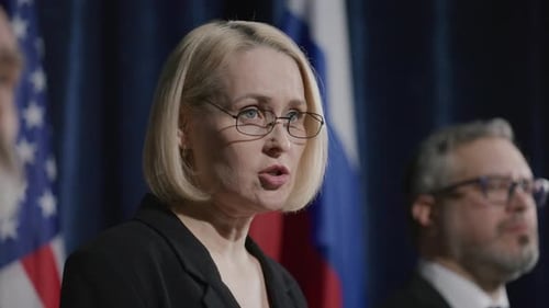 Woman Speaks at Press Conference with Flags