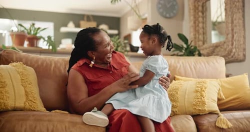 Grandmother and Granddaughter Sitting on the Couch Laughing