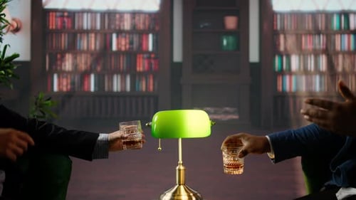 Two People Toasting with Drinks Near Bookshelves
