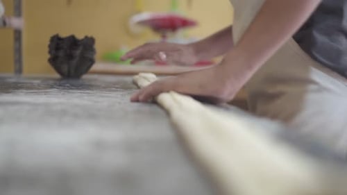 Pastry chef shaping dough on the countertop, preparing it for baking in the kitchen.