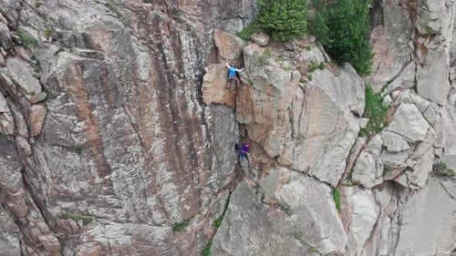Climbers Ascending Steep Cliff Face Working Together