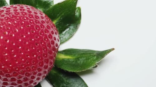 Erdbeeren mit grünen Blättern. Dreht sich. Ansicht von oben auf weißem Hintergrund, Nahaufnahme.