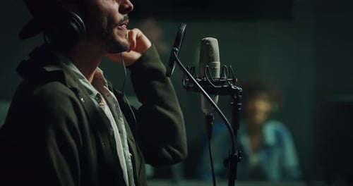 A professional african female sound producer with headphones is recording a new song with an young