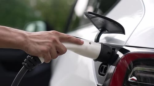 Charging White Electric Car With Charging Cable Outdoors