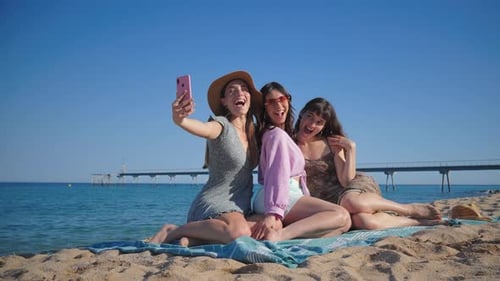 Three Dressed Women Lying on the Sand of the Beach Taking a Selfie Portrait with a Cellphone Group