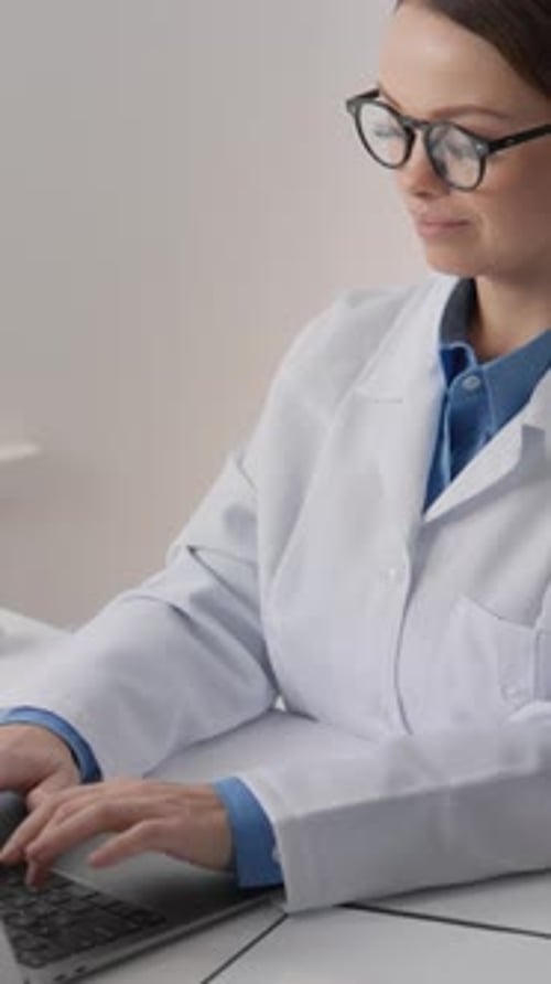 Woman Doctor Typing on Laptop in Hospital Office