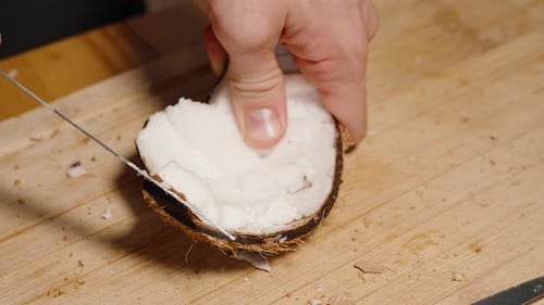 Cutting fresh coconut with knife on cutting board
