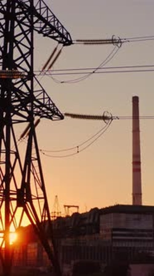 Hermosa puesta de sol sobre las líneas eléctricas. Paisaje de torres eléctricas de alta tensión al atardecer. Vídeo vertical