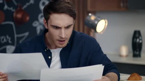 Focused Businessman Reading Documents at Home Office. Smiling Business Man Comparing Financial