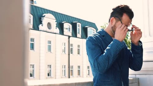 Stylish Man Putting on Sunglasses Outside in City