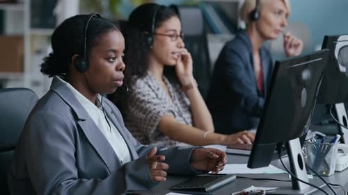 Operators in Headsets Consulting Online Clients in front of Computers