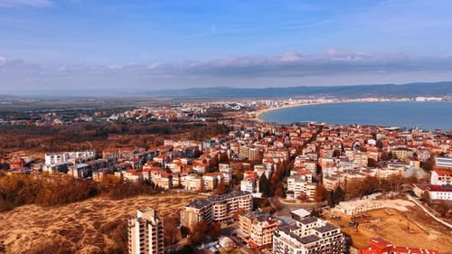 Footage over the cityscape in autumn season. Blue seascape and mountain range at backdrop.