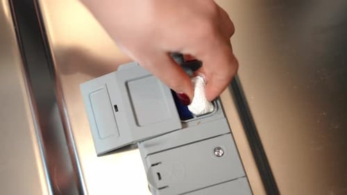 Top View Closeup Female Hand Placing Detergent in Dishwasher Dispenser Leaving Closeup