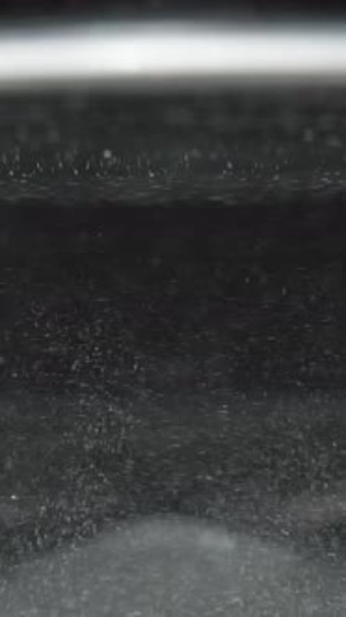 Vertical video. More undissolved powder particles spinning in the water, highlighting the mixing