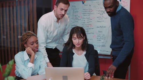 Diverse Team Collaborating on Laptop in Modern Office