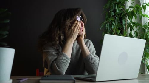Woman at Desk With Laptop Covers Face