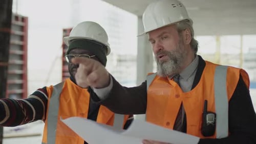 Two Men Discuss Building Plans at Construction Site