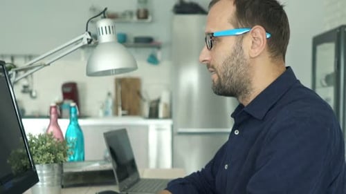Junger Mann arbeitet am PC-Computer und sitzt zu Hause am Tisch Erwachsener