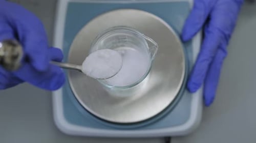 Technicien de laboratoire ajoutant des mesures précises de composés chimiques à l'aide d'une balance numérique