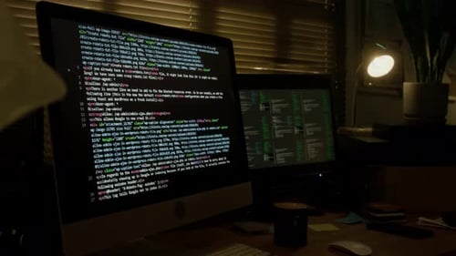 Dos monitores que muestran el Código en la habitación del programador con poca luz