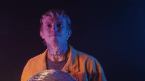 Man Holding Disco Ball Under Neon Lights