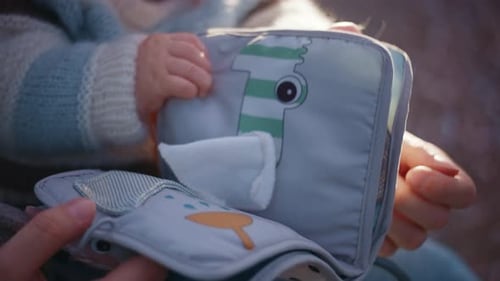 Baby Playing with Book in Caregiver's Lap