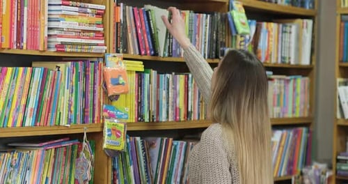 The blonde chooses a book in the store