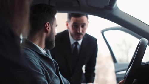 Man looks at car with salesman in dealership