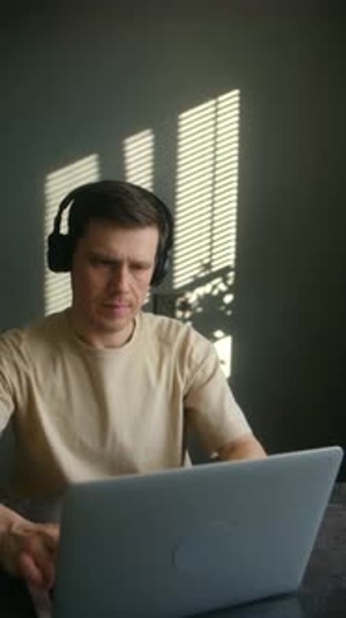 Man Working on Laptop With Headphones at Home