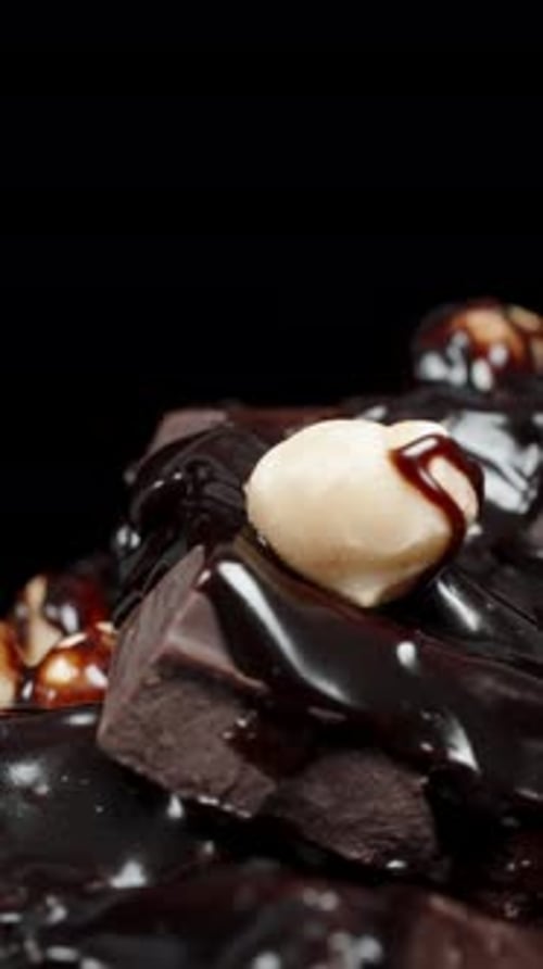 Vertical video. A stack of chocolate bars covered with dark chocolate and sprinkled with nuts