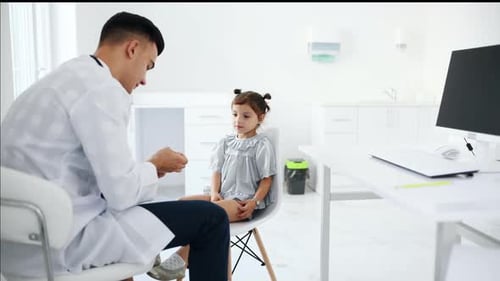 Little girl have a visit in the clinic with doctor. She taking out medical tonsil out of package