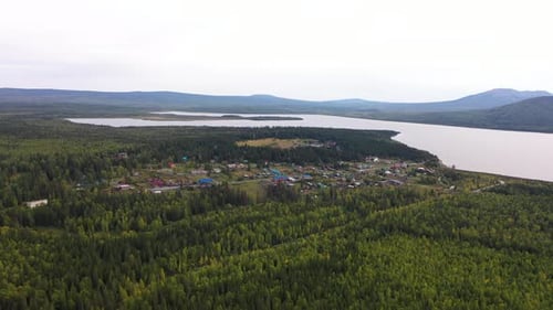 Flying Over a Village Far From the Bustle of the City in the Middle of a Forest Mountains and a