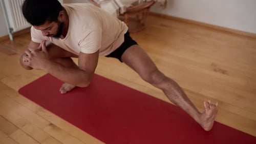 Man Stretching on Yoga Mat in Light Home