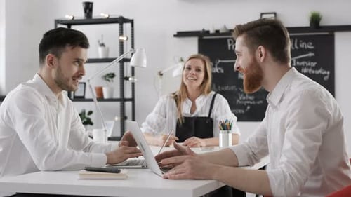 Jovens colegas de trabalho diversificados discutindo o sucesso de uma startup em um ambiente de trabalho moderno em um loft