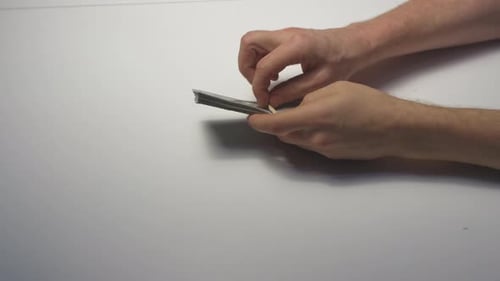 Hands Removing Rubber Band From Stack of Cash
