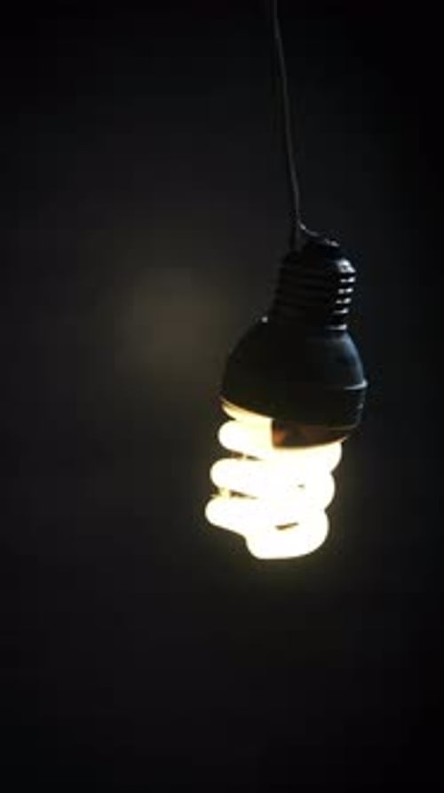 Vertical Spiral Fluorescent Lamp Flickers Lights Up Sways on an Electric Wire