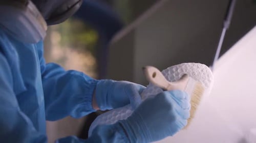 Scientist nettoie les semelles de chaussures imprimées en 3D, en éliminant l'excès de matière et en perfectionnant le produit final.