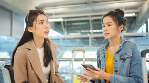 Women Travellers Checking Tickets in Airport Waiting Area