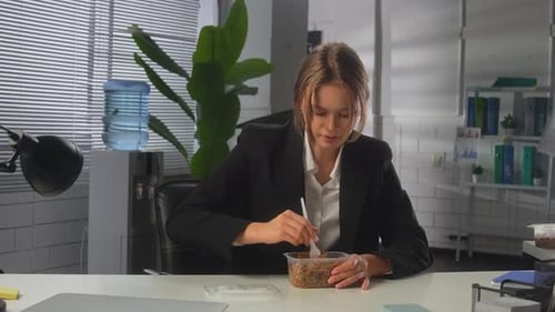 Woman Enjoying Noodles in an Office Setting During a Casual Lunch Break