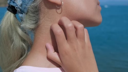 Woman Scratching Itchy Neck in Front of Ocean
