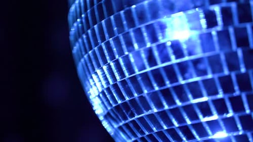 Disco ball reflecting blue lights during lively dance party atmosphere