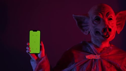 Scary Man with Pig Mask Holding Green Screen Smartphone